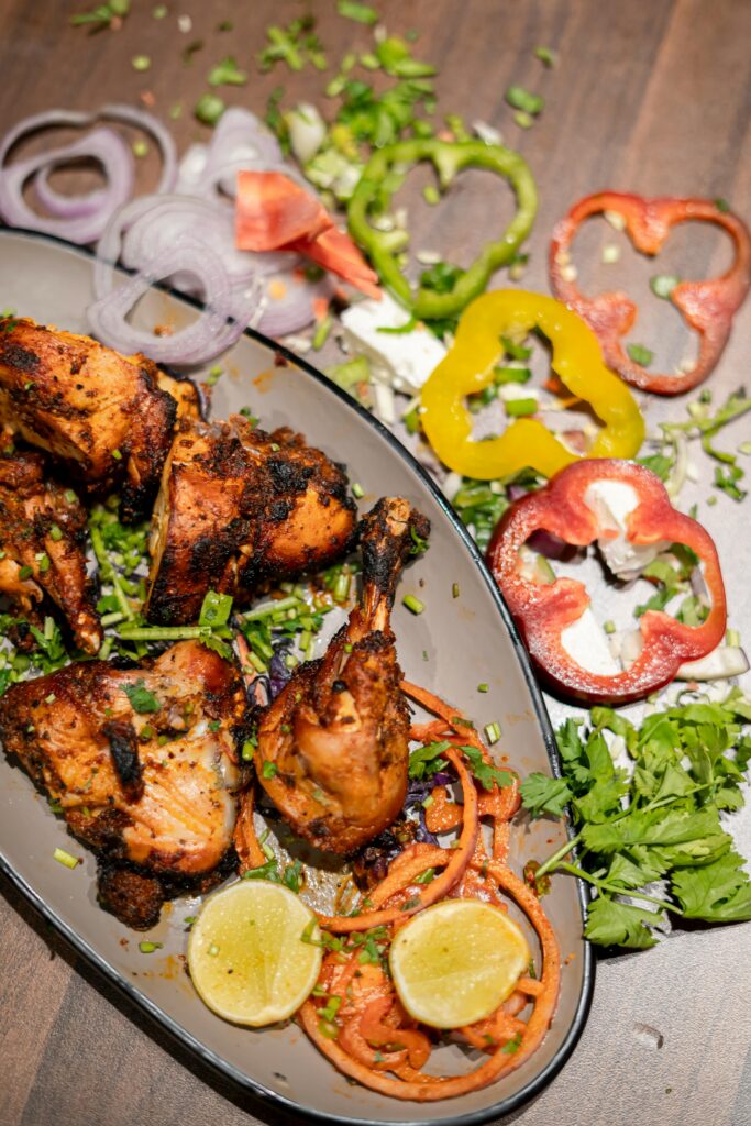 Savor the vibrant flavors of tandoori chicken with fresh vegetables, perfect for food photography enthusiasts.